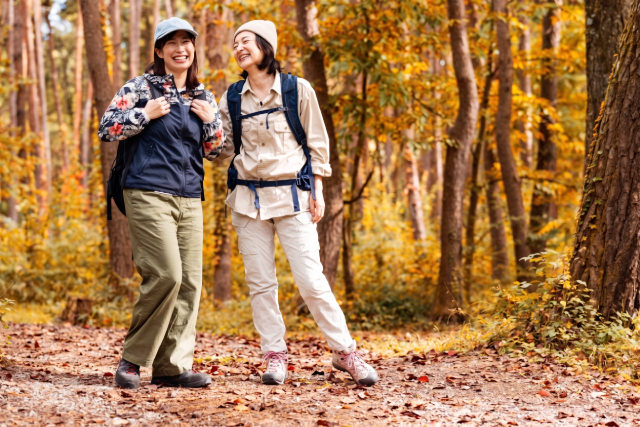 紅葉の木々を背景にハイキングをする二人の女性